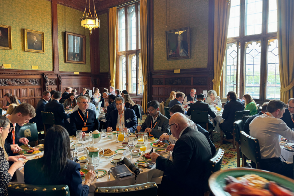 A full room of financial services professionals seated in a formal chamber at the House of Commons, attending Regs & Eggs 2026